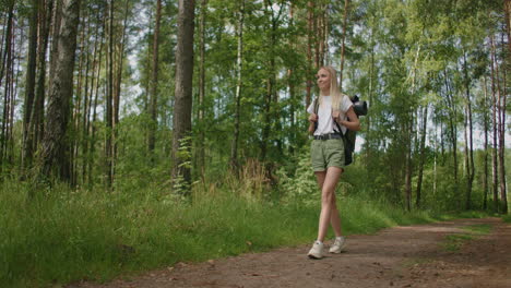 General-plan:-Traveling-Happy-Caucasian-blonde-woman-with-backpack-walking-on-path-the-tropical-forest